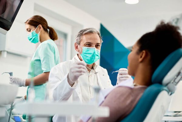 Group Dental Insurance - Woman Getting Her Teeth Cleaned by a Dentist and an Assistant