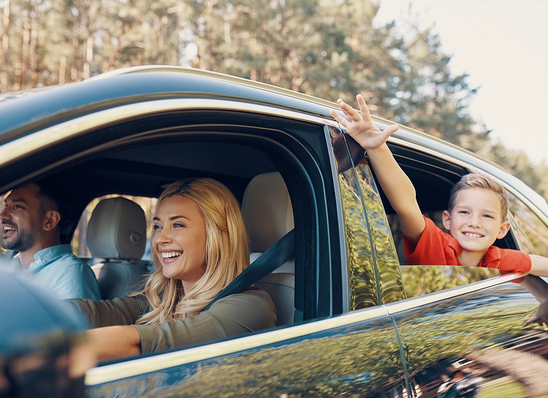 Personal Insurance - Young Beautiful Family With a Little Boy Having Fun and SMiling While Driving in the Car